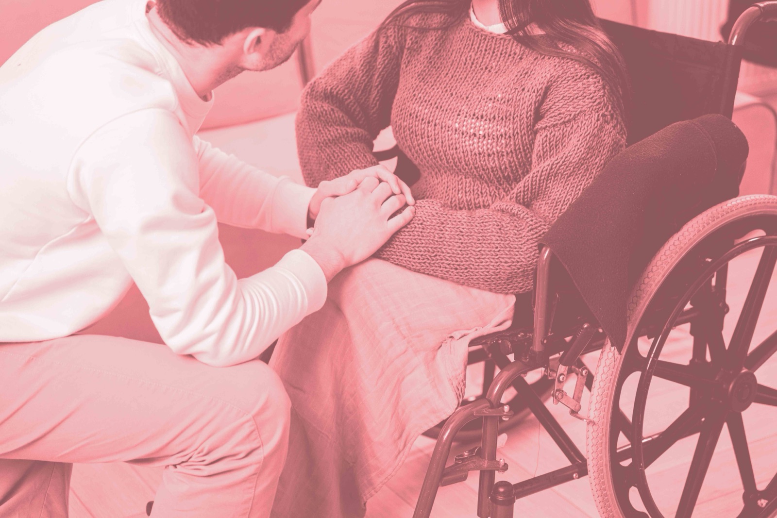 Une personne tenant la main d’une autre assise en fauteuil roulant